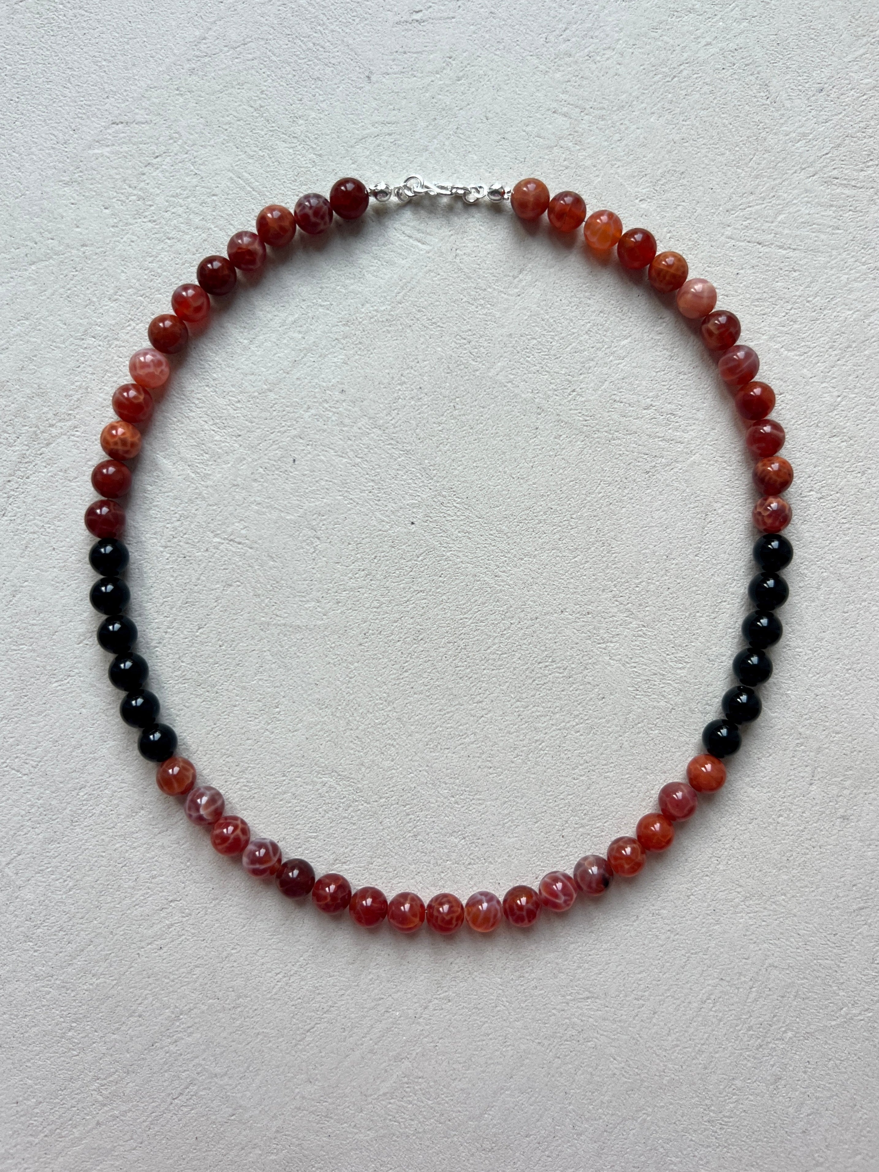 Beaded necklace with red and black beads on a light gray background