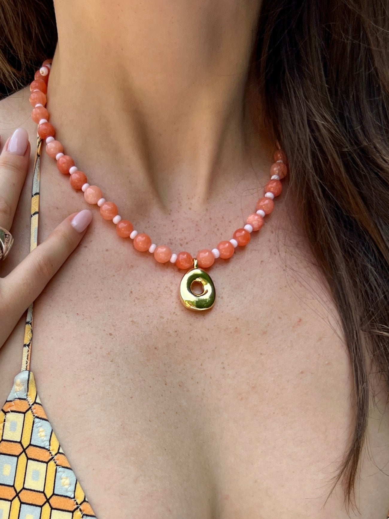 Woman in a orange beaded necklace by a poolside